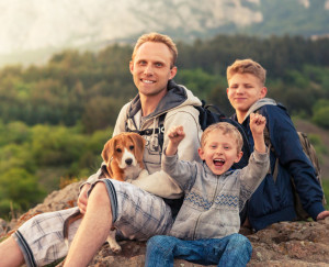 Father and two sons holding their dog in the mountains
